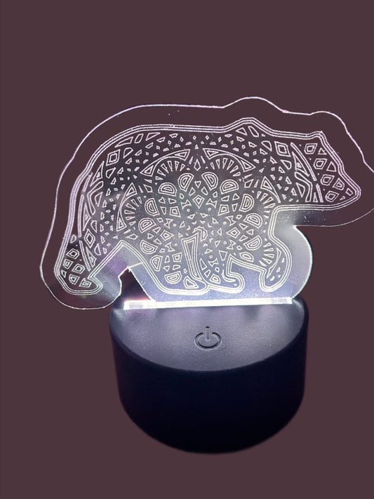 Circular Nightlight base illuminating white light onto an engraved acrylic cut out of a bear with an engraved mandala center